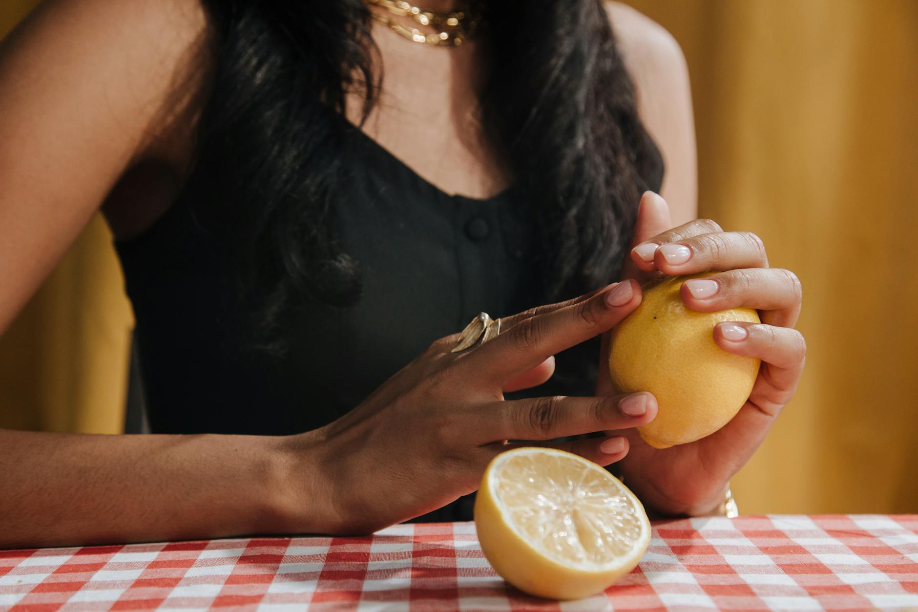 A woman's hand holding a pink clitoral vibrator surrounded by art books and plants, symbolizing self-care and intimate wellness.