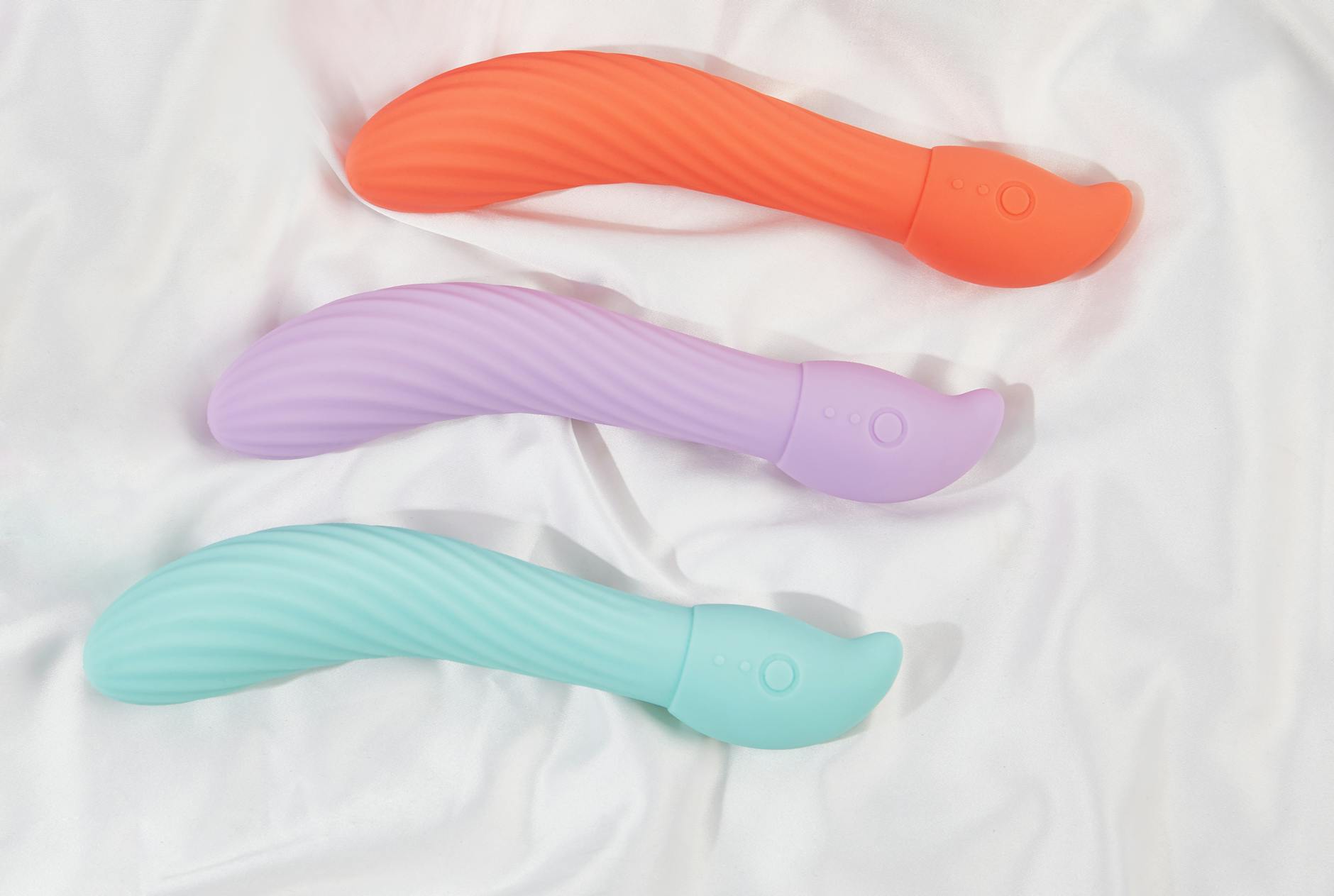 Colorful vibrators arranged on white fabric, showing texture and design variety for different preferences.