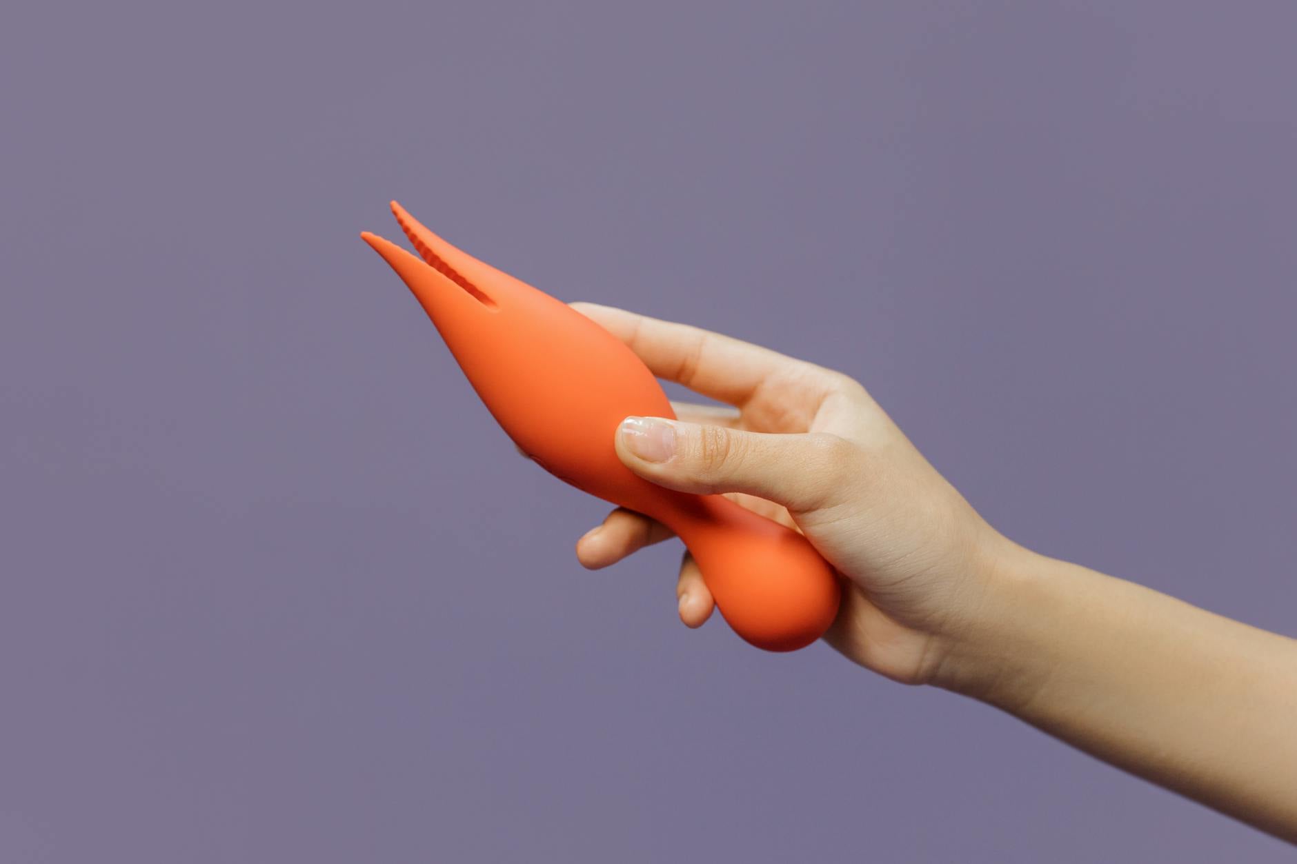 A hand holding a lemon-colored vibrator against a minimalistic backdrop, representing accessible pleasure during recovery