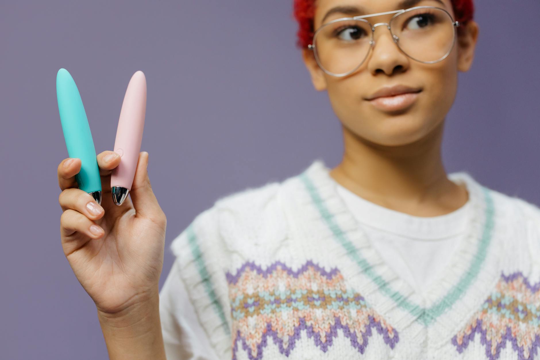 Person holding colorful vibrators against a purple background, representing reconnection with pleasure